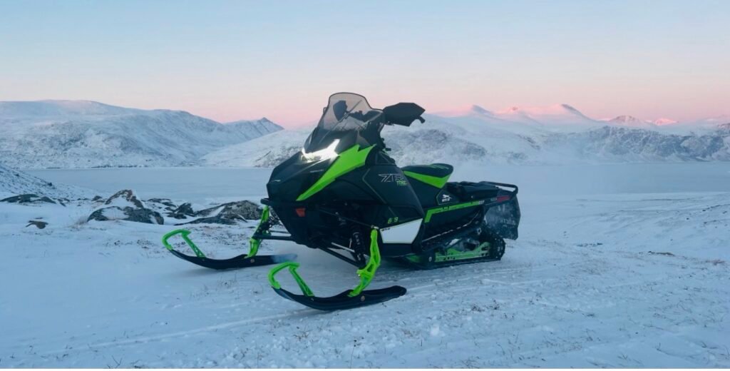 Arctic Cat ZR snowmobile in a snowy mountain landscape at dusk