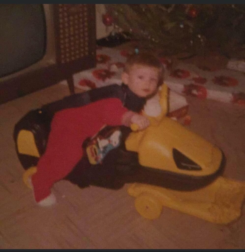 Toddler Doug on his first toy snowmobile
